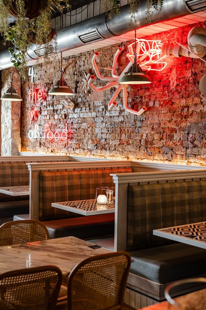 Booth seating area at Frankie B's Food House Parramatta with neon signage and rustic brick wall.
