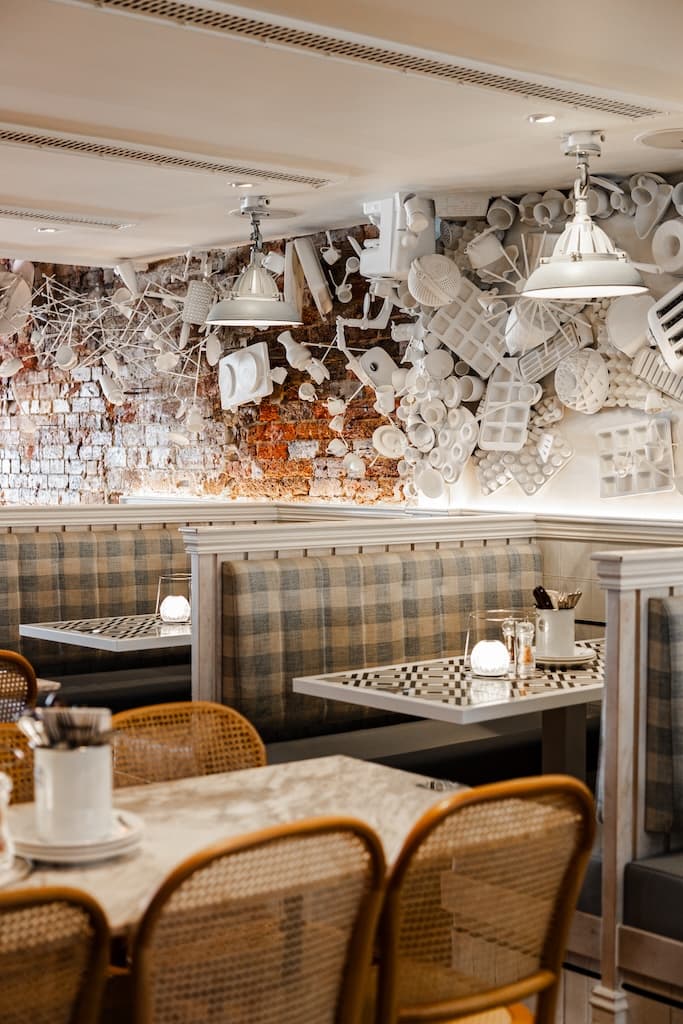 Booth seating with checkered upholstery and a wall decorated with white kitchen utensils at Frankie B's Food House Parramatta.