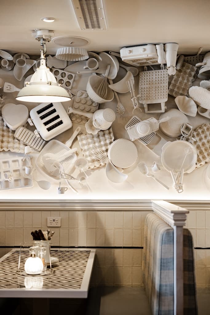 Cozy booth seating with creative wall decor made of white kitchen utensils at Frankie B's Food House Parramatta.